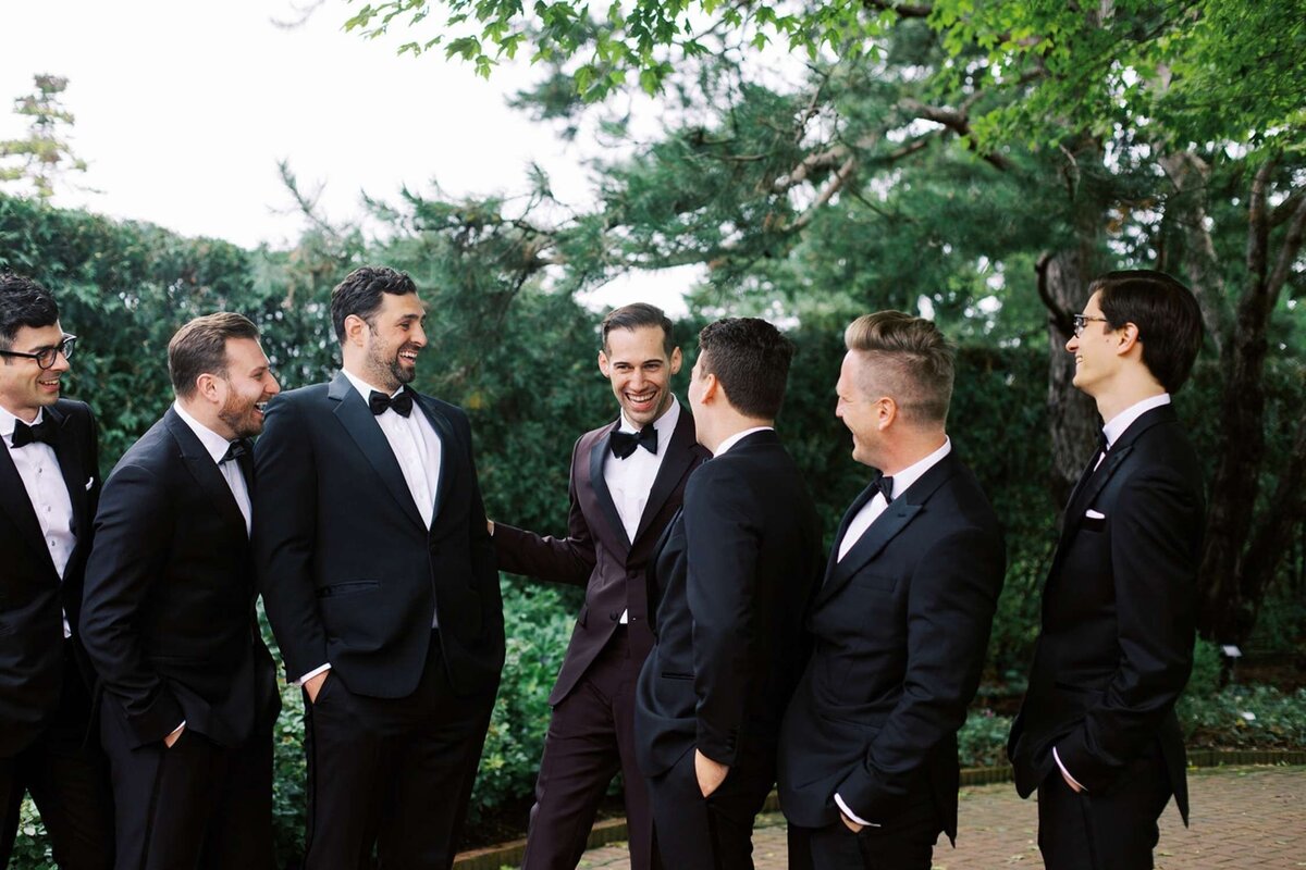 Groomsmen in black tie  relaxing before the ceremony at a luxury Chicago outdoor garden wedding.