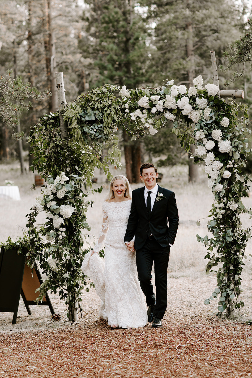 Lake Tahoe Wedding Planners couple under white floral arch at venue Mitchell's Mountain Meadows Sierraville near Truckee, Joy of Life Events image by The Shepard Photography
