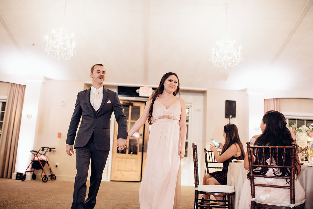 Wedding Photograph Of Groomsman And Bridesmaid Holding Hands While Walking Inside The Reception Hall Los Angeles