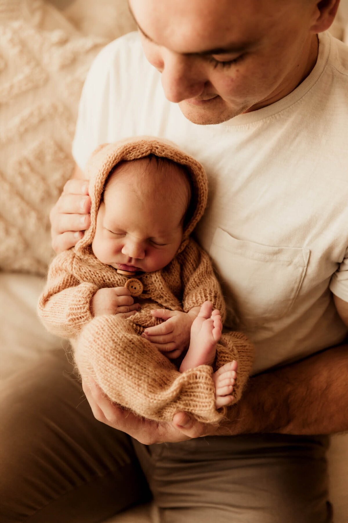 Newborn baby boy being held by his father and sleeping.