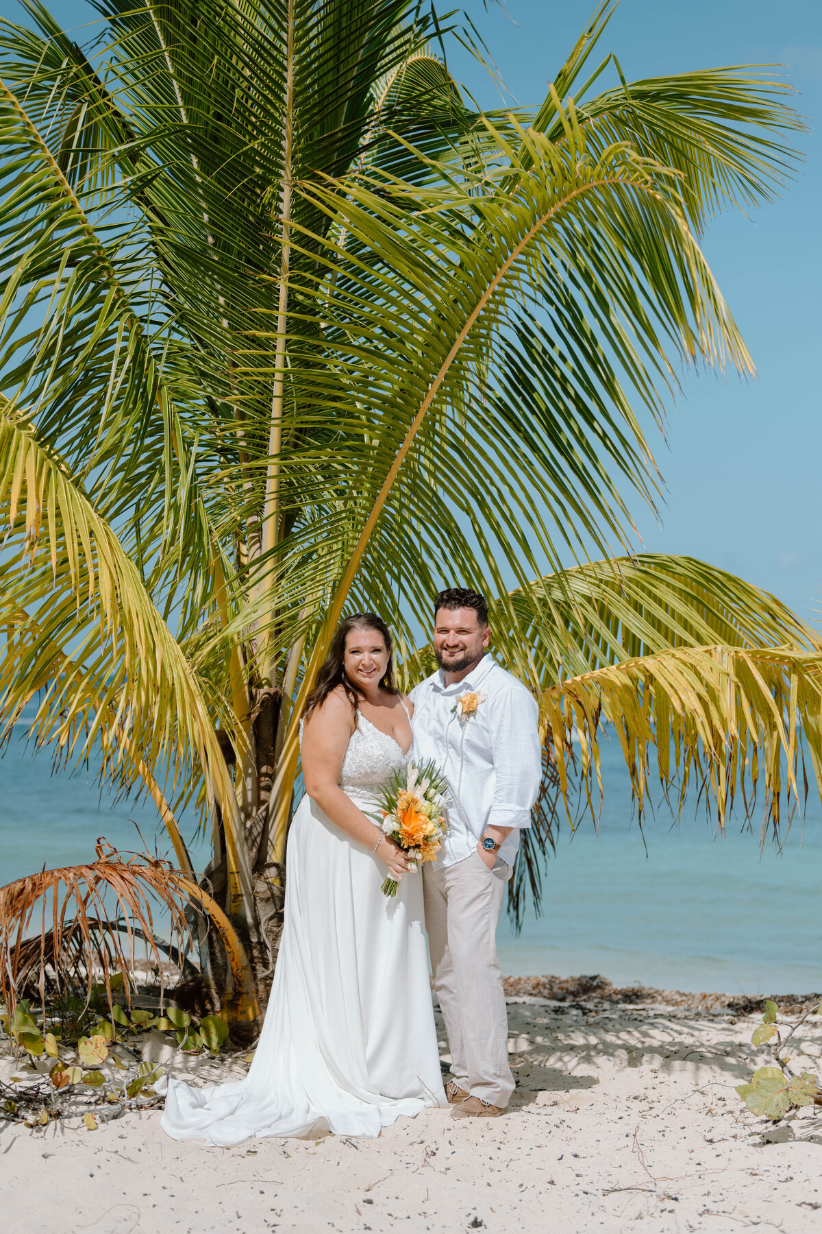 a bride and groom by a palm tree at Mr Sanchos in Cozumel