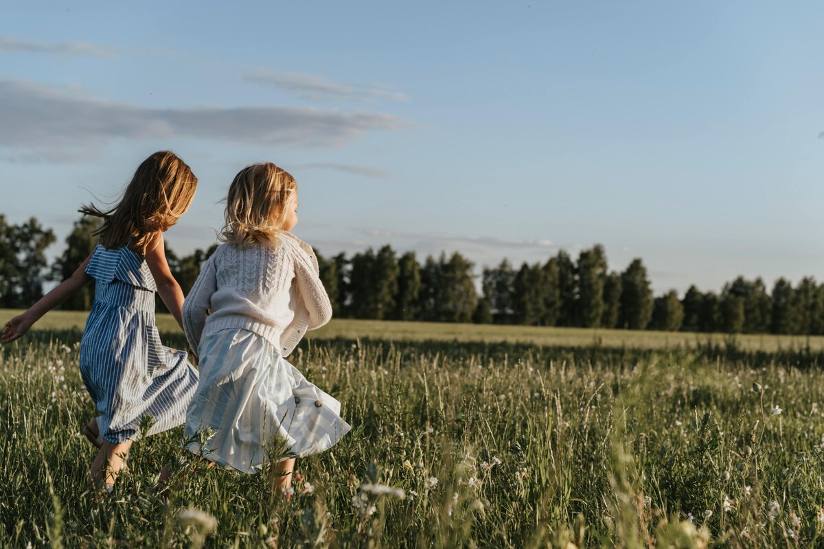 Two girls running in grassy field | Rooted Within Santa Barbara educational evaluations and guidance