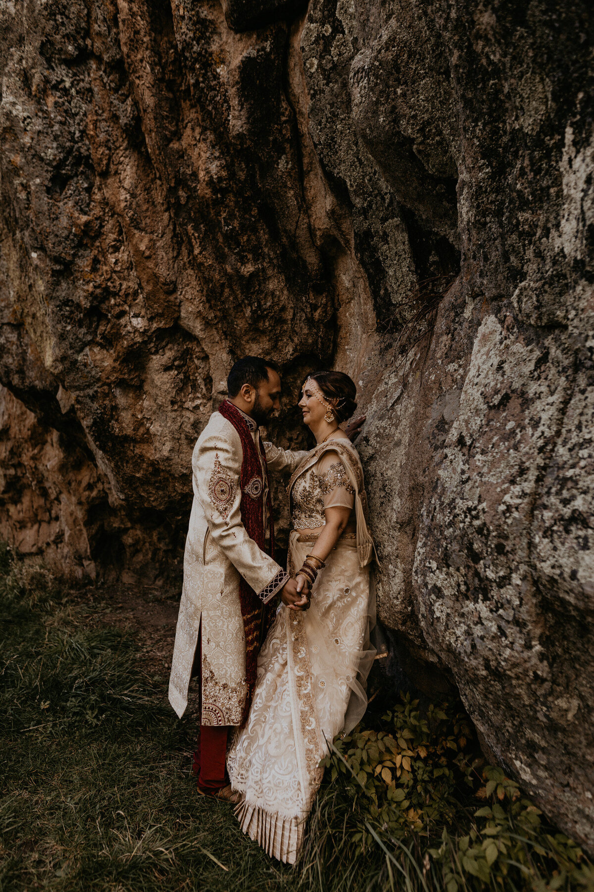 bride and groom leaning against a massive rock in New Mexico