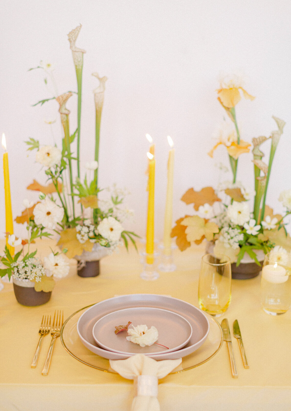 Modern centrepieces of orange and green flowers on a yellow tablecloth at a Montreal wedding reception.