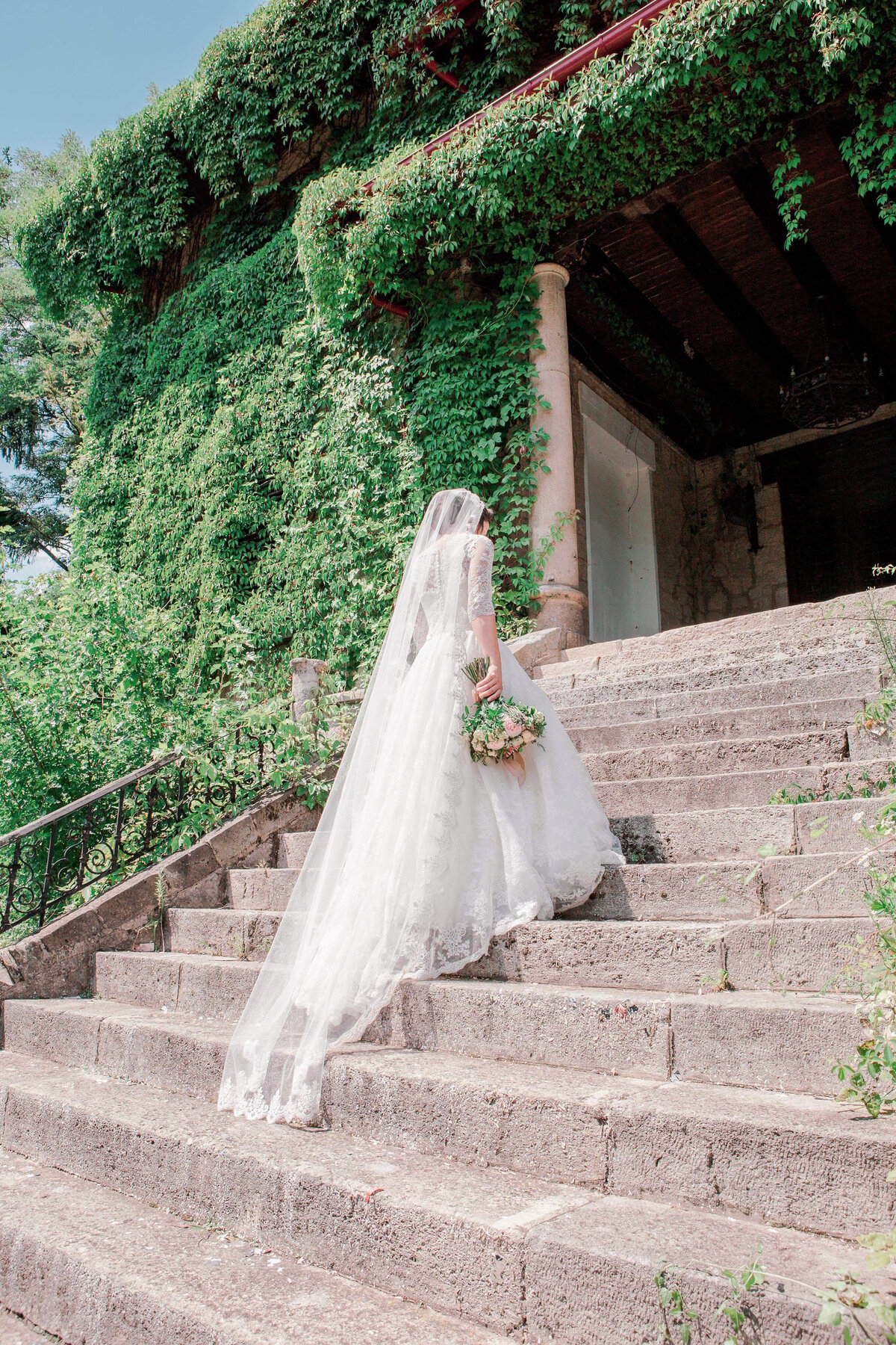 A bride in a wedding dress walks up a staircase on her wedding day.