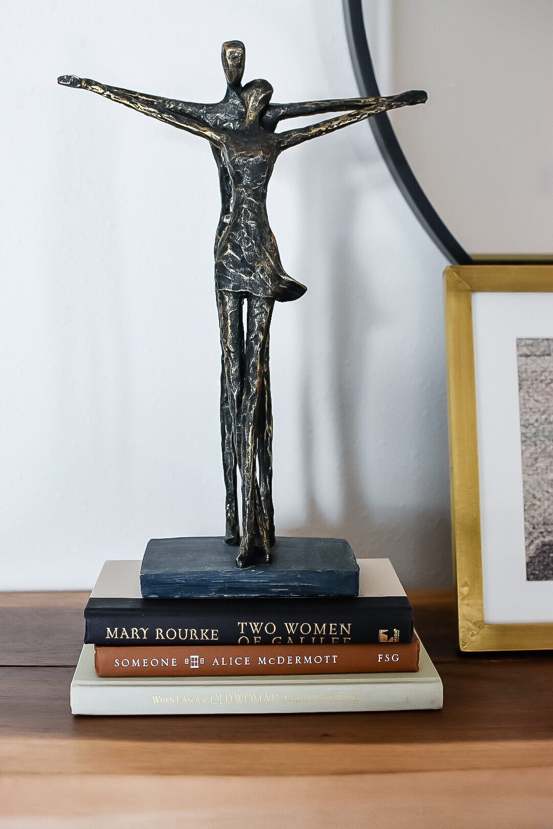 A black metal statue of two people holding hands sits on a stack of books