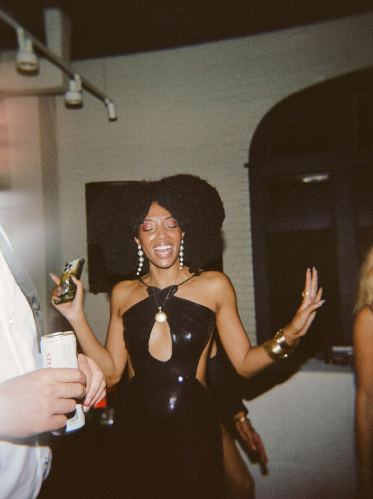 a woman with cool style & afro hair laughs at a wedding afterparty in Detroit
