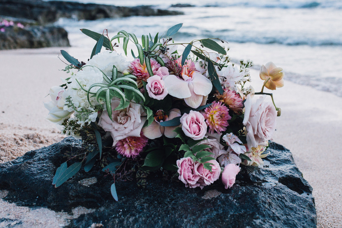 Bridal bouquet resting on rock by the ocean after elopement