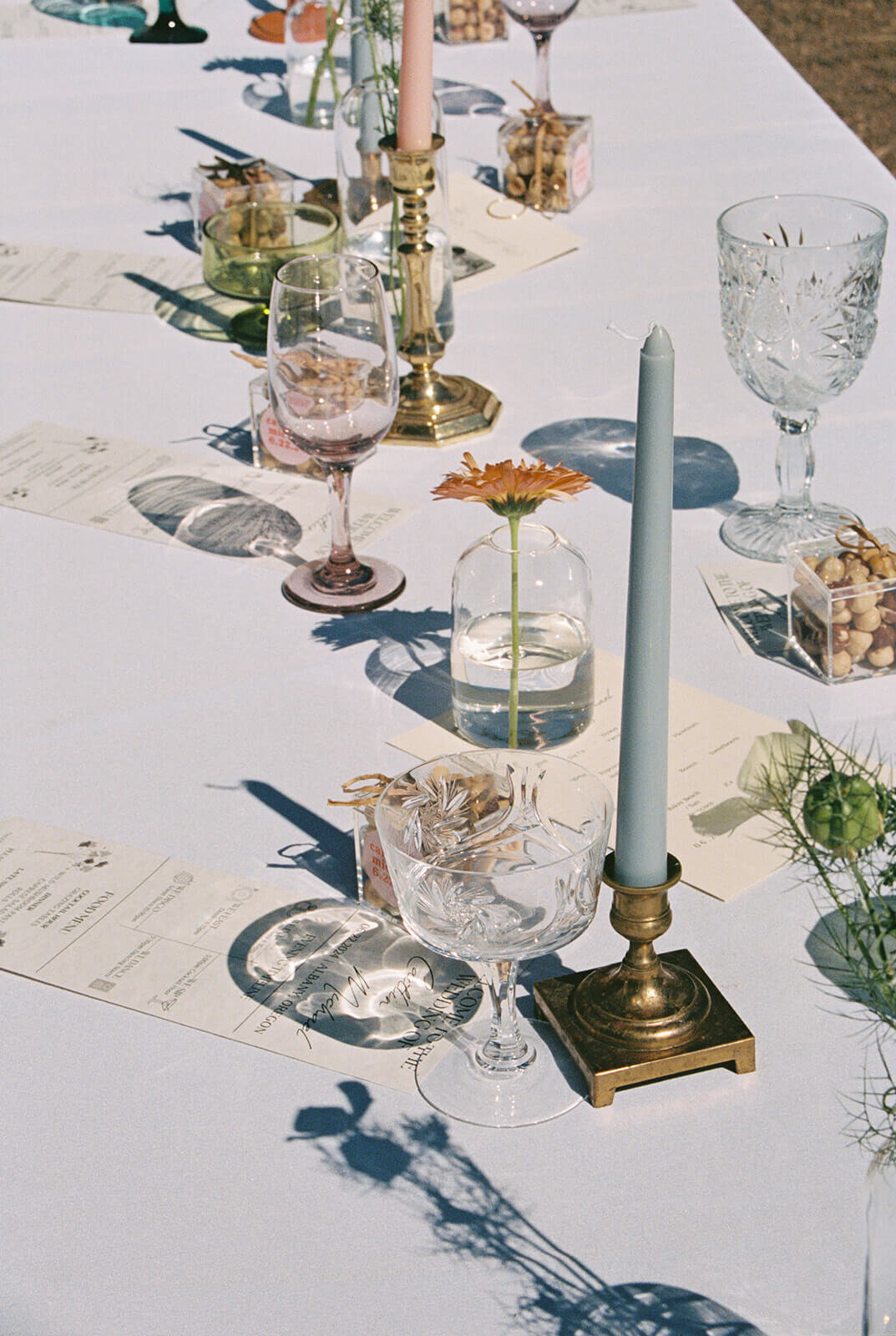 A table at a wedding with glasses, candles and menus.