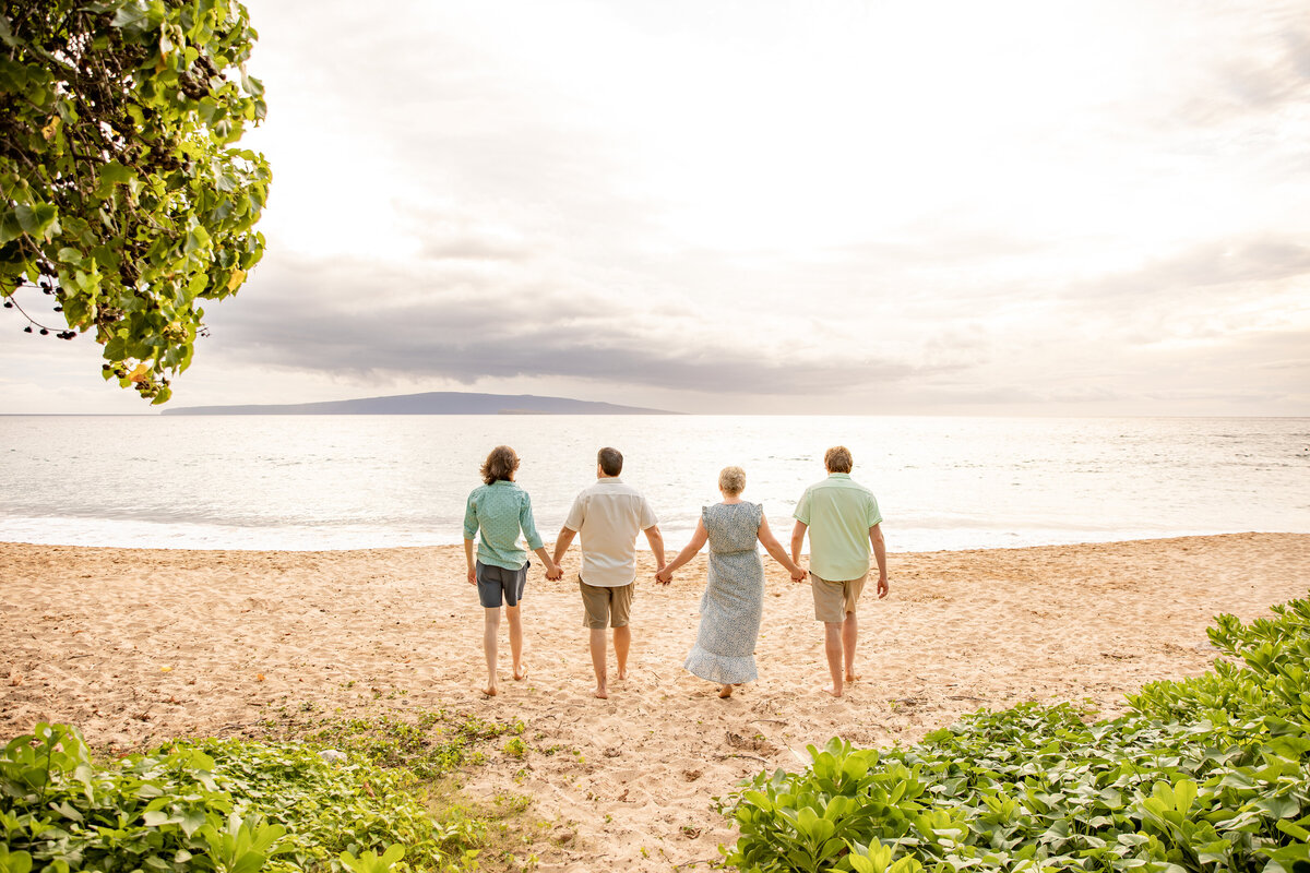 Maui Family Photographers capture young family holding hands and walking into ocean