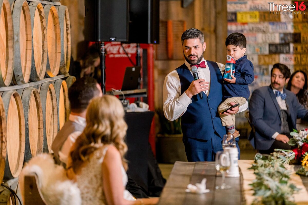 Bride and Groom look on as the best man delivers his toast