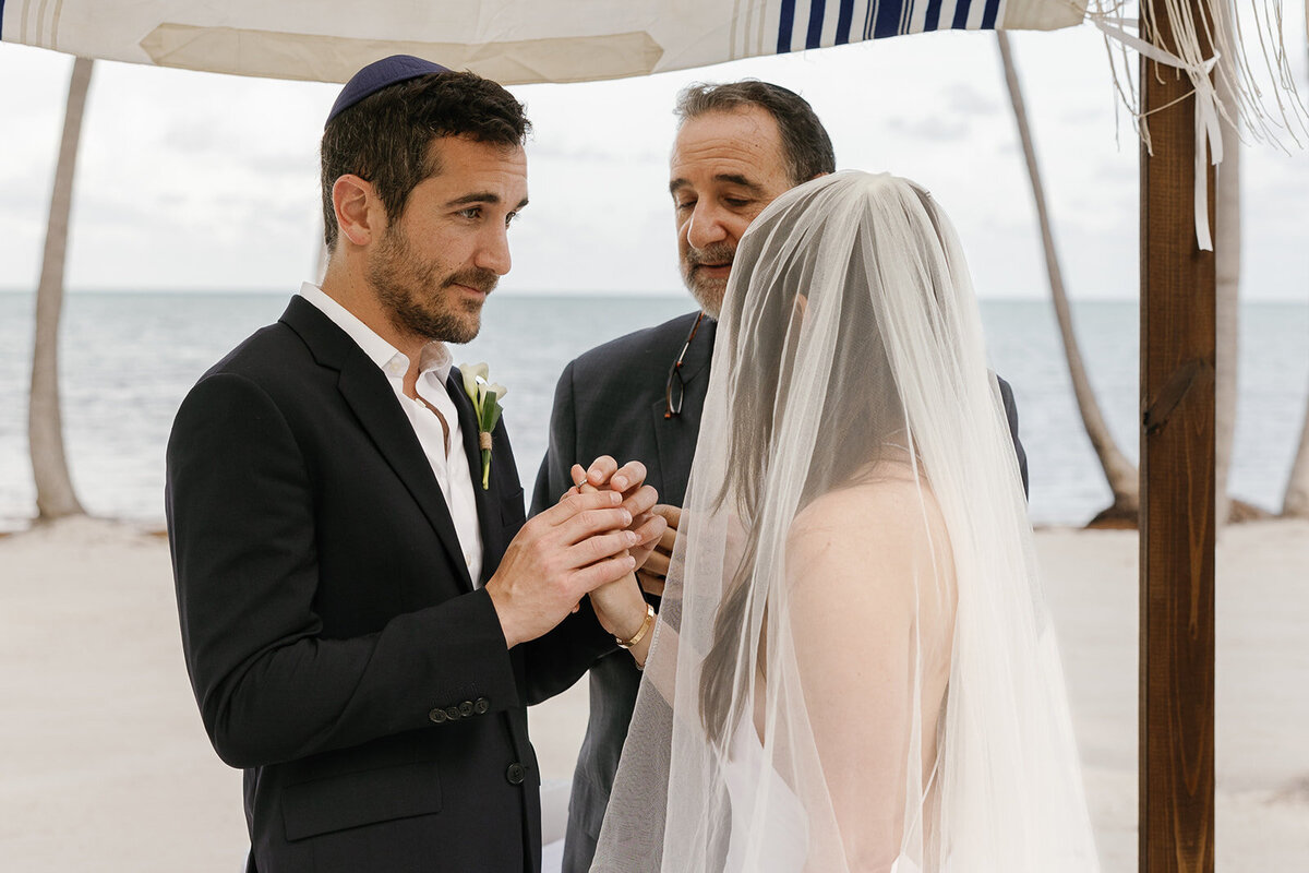 Evan gently places the wedding ring on Minette’s finger during their intimate ceremony in Islamorada. Destination wedding photography by Claudia Amalia.