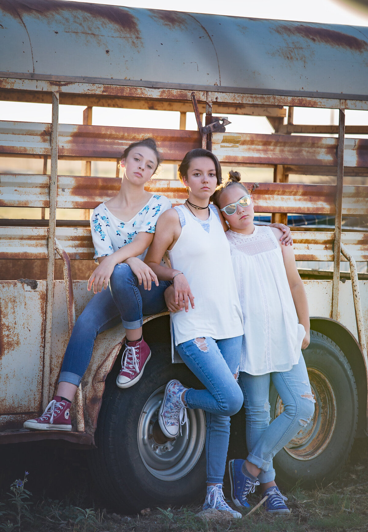 senior girls standing next to old stock trailer