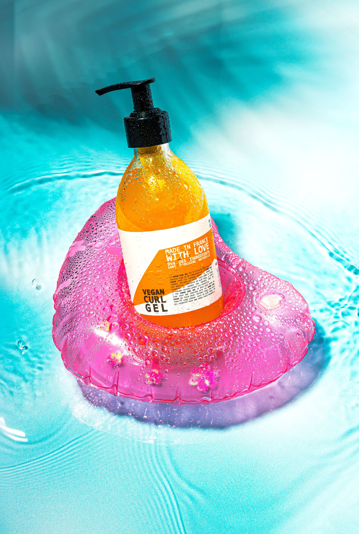 Photo du gel coiffant Cut By Fred posé sur une base rose flottant dans l’eau bleue, Studio Helloday.