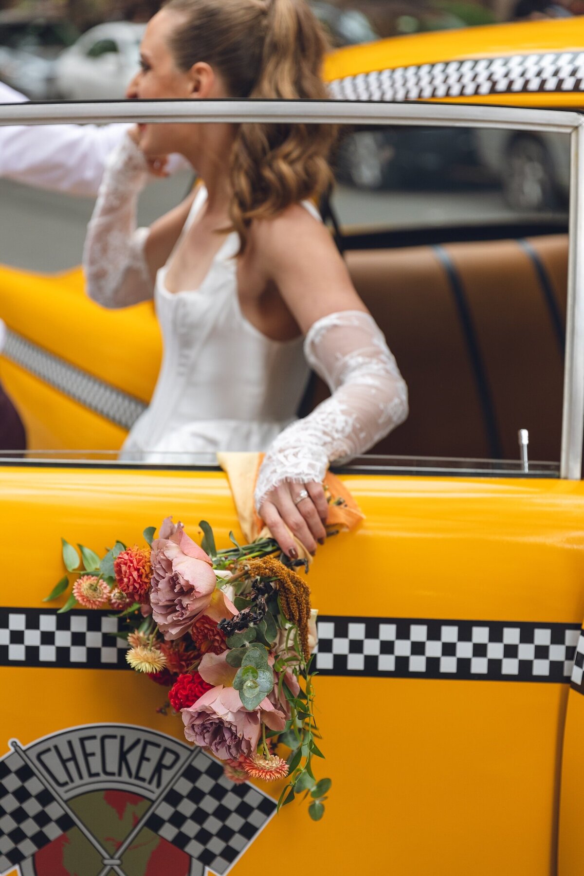 Bride stepping out of classic yellow NYC taxi with bouquet