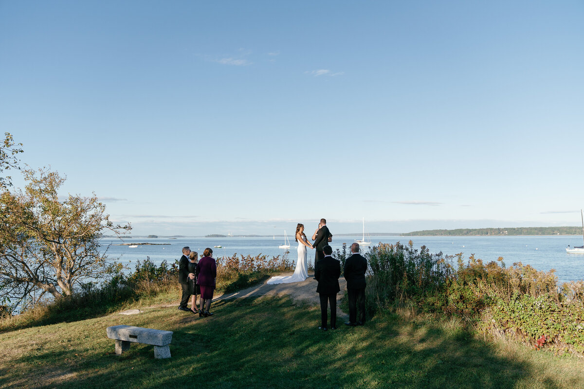 Couple holding hands during their wedding ceremony next to the ocean by east coast photographer Shelby Ann Photos