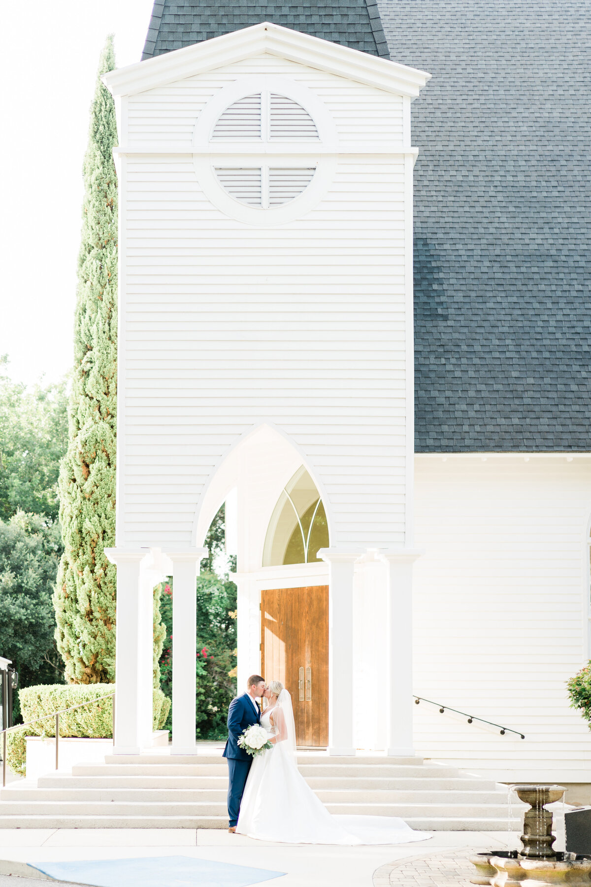 Bride and groom standing outside white church in Alabama