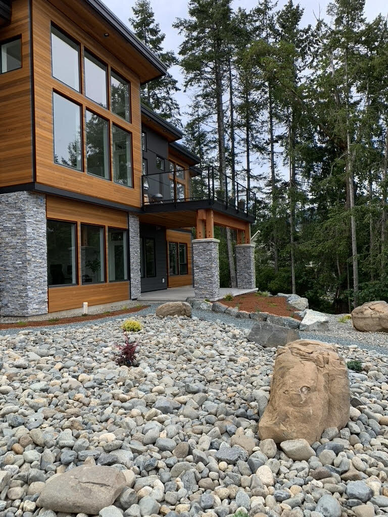 Modern home exterior design with cedar, rock , and minimal landscape design.