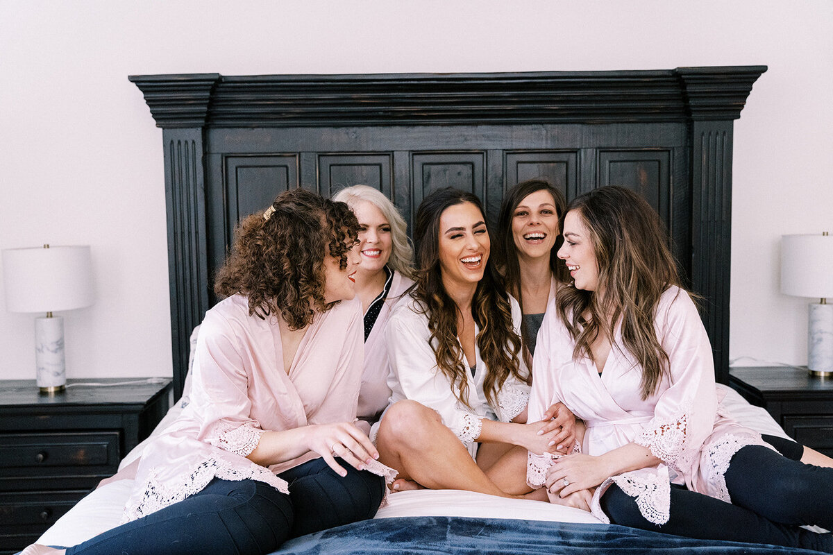 bride sitting on a bed with bridesmaids