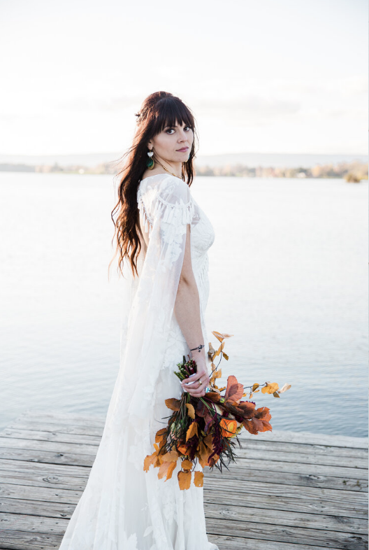 bride holding a fall bouquet posing on a dock