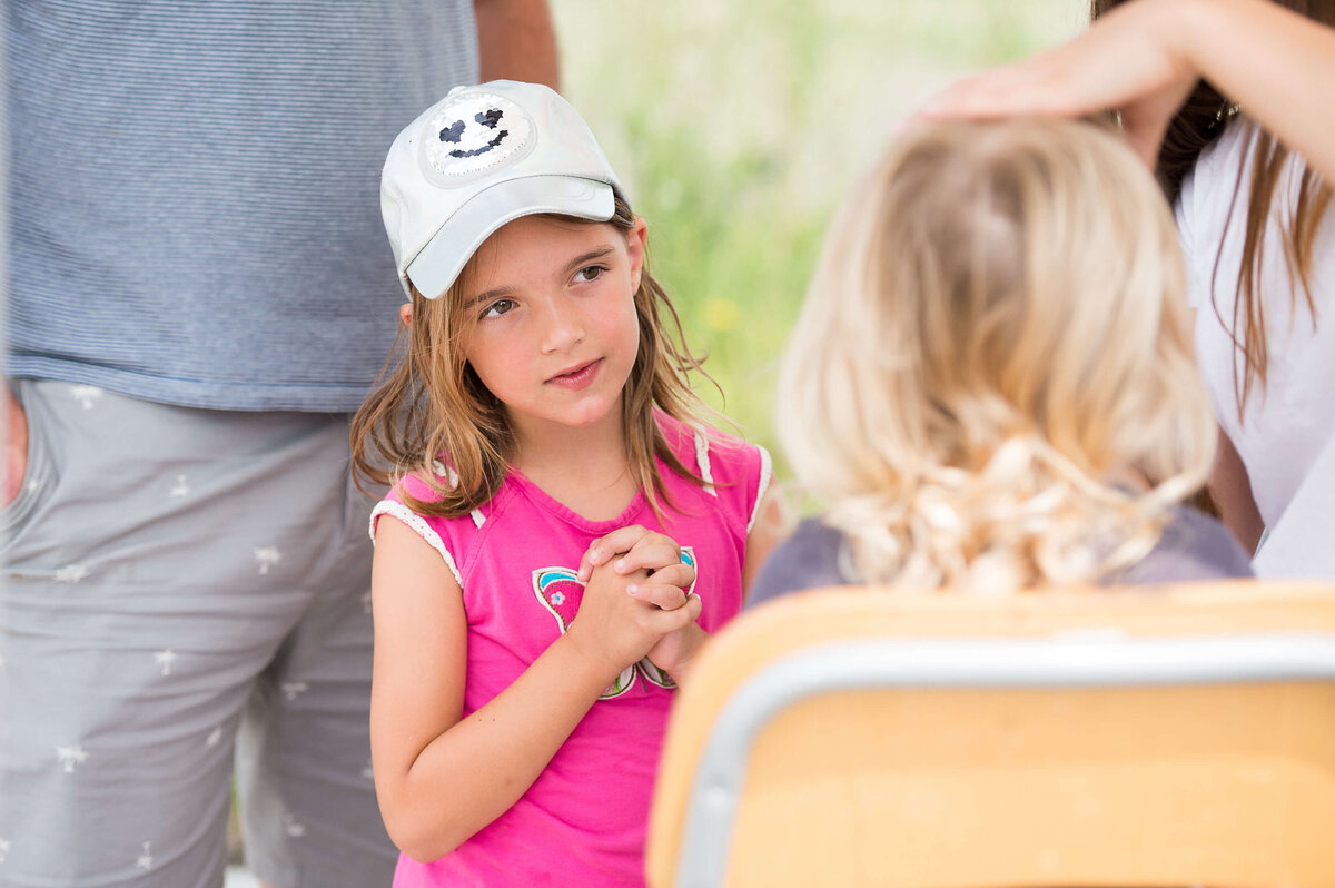 a little girl in a pink t-shirt showing excitement on her face while she waits to have her face painted during a corporate children's event.  Captured by Ottawa Event Photographer JEMMAN Photography COMMERCIAL