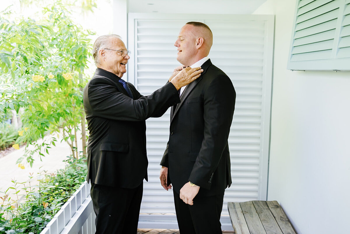 A heartfelt moment between the groom and his father as he adjusts his son's bow tie before the wedding ceremony. A beautiful father-son bond captured by Claudia Amalia Photography at Stephanie and Bradley’s Islamorada wedding.