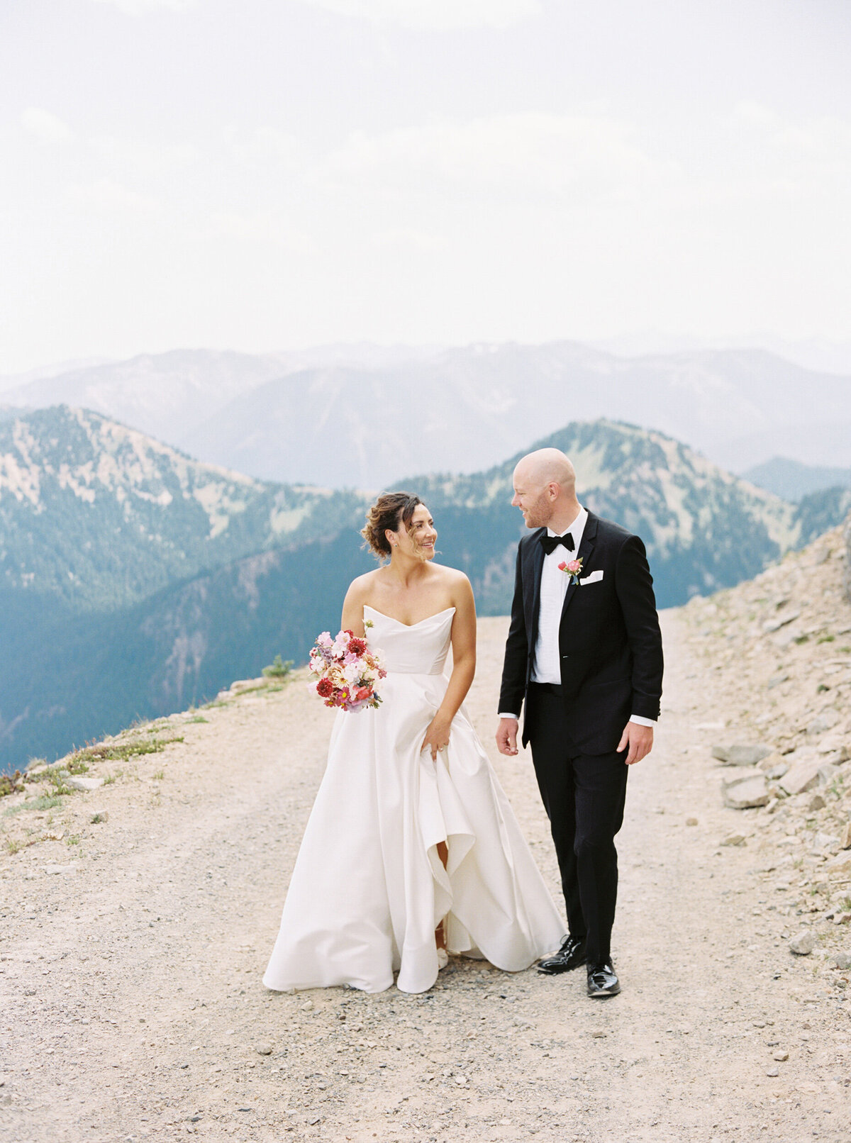 bride and groom walking at the top of a mountain