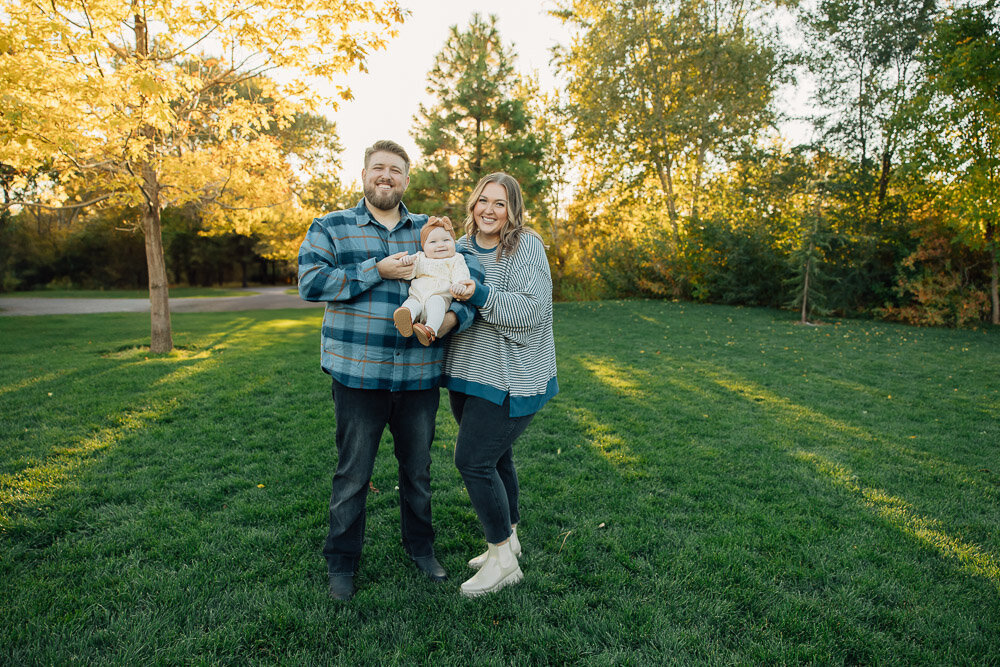 utah couple with young baby smiles at their family photo session at highland glen in Highland, Utah