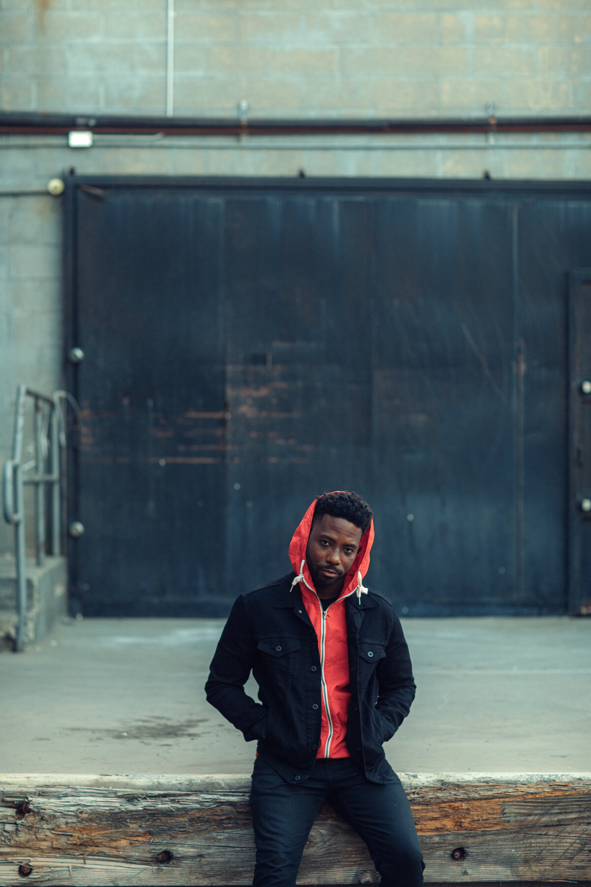 Portrait Photo Of Young Black Man In Orange Hoodie Sitting On a Cement Ground Los Angeles