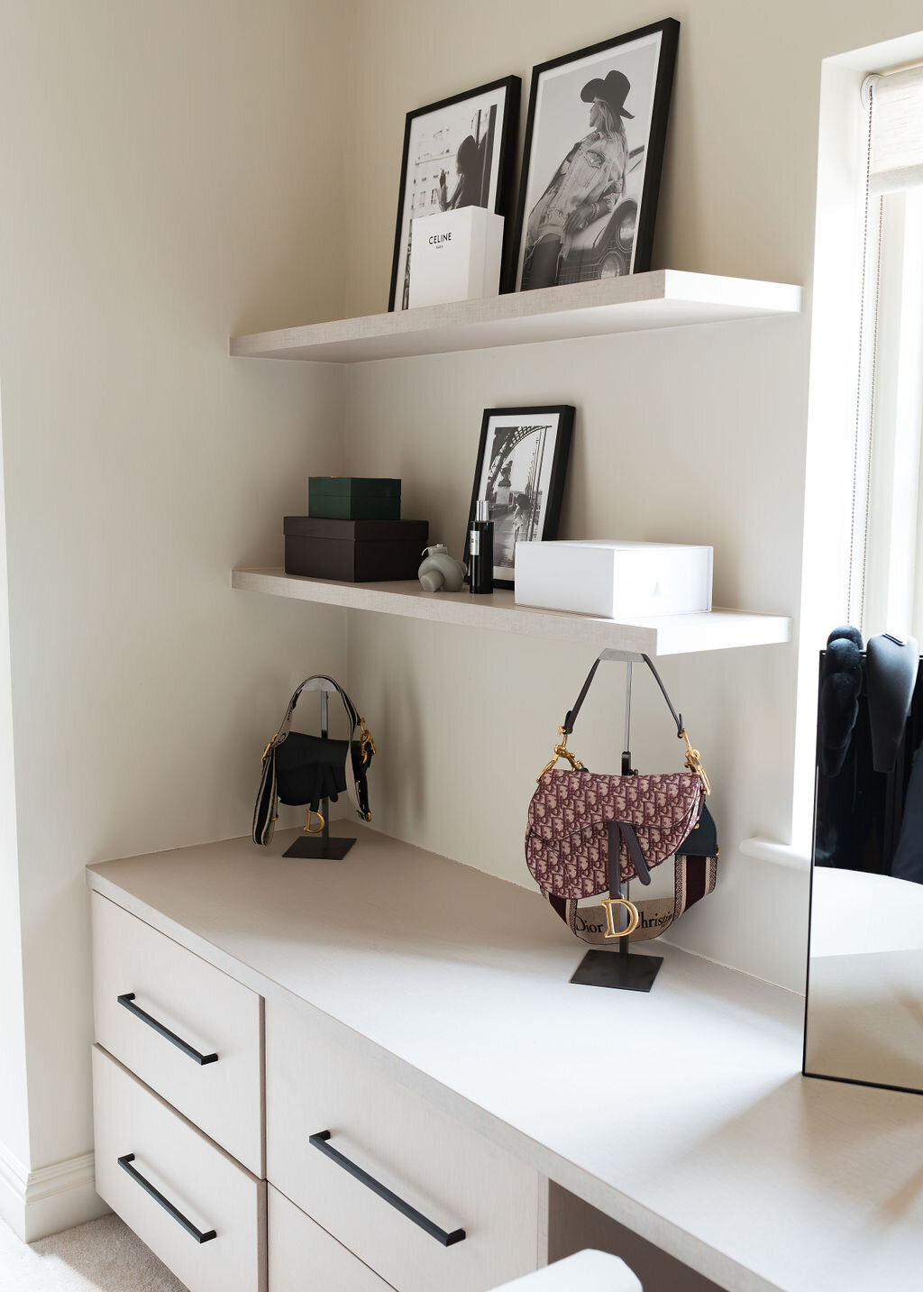 A modern, light-filled walk-in closet with white cabinets and built-in shelves containing handbags and storage baskets