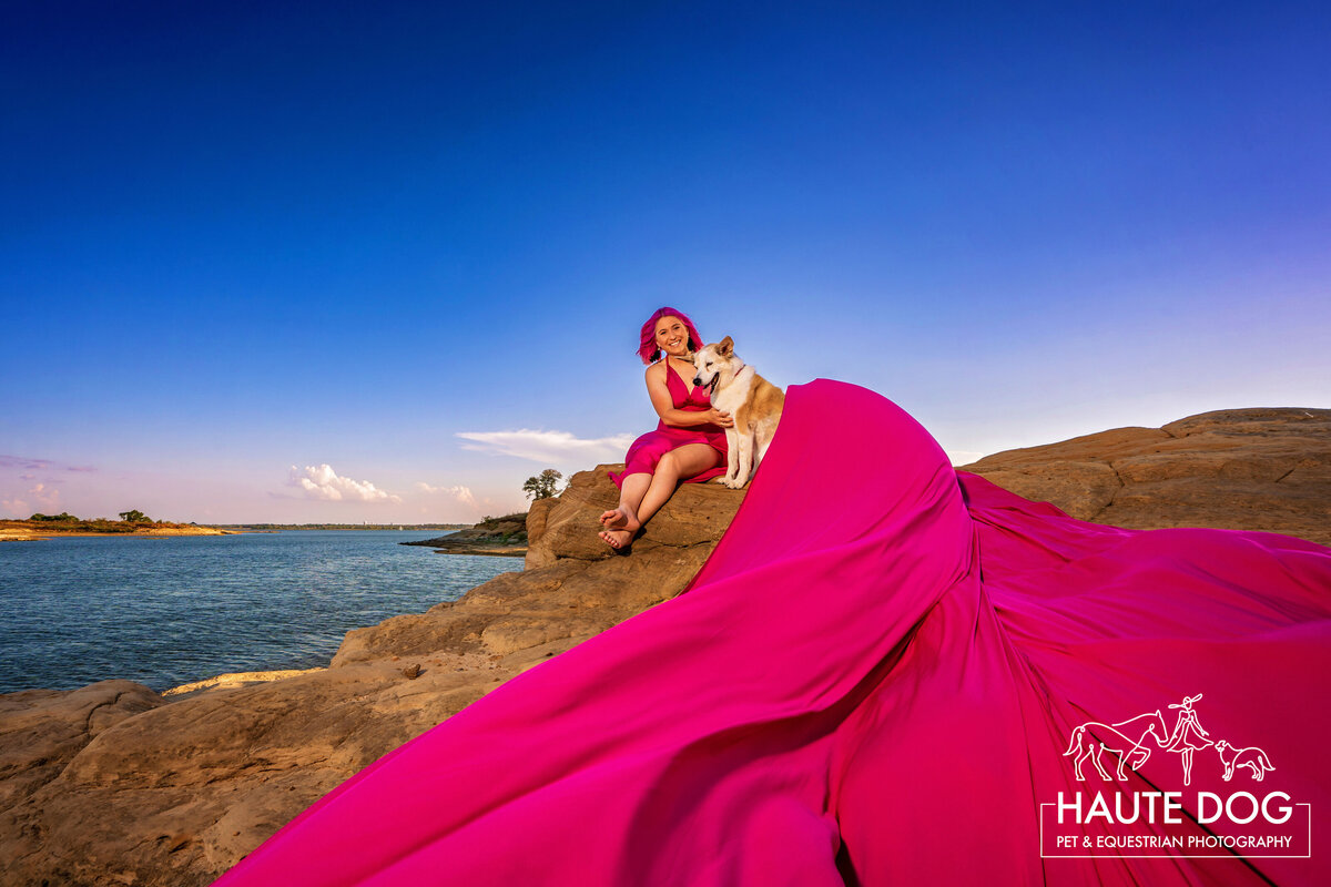 Dog mom sits on the bluffs of Grapevine Lake in Flower Mound as her long pink flying dress wraps around her dog.