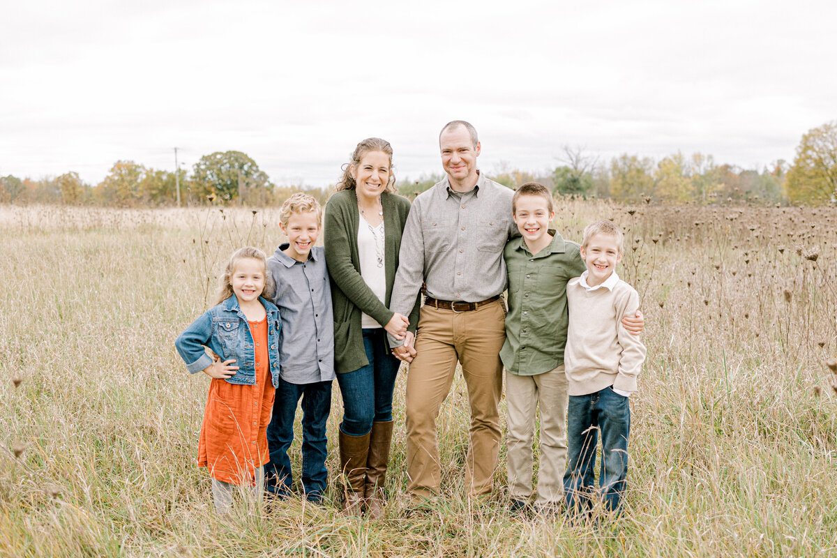 family standing in a field smiling