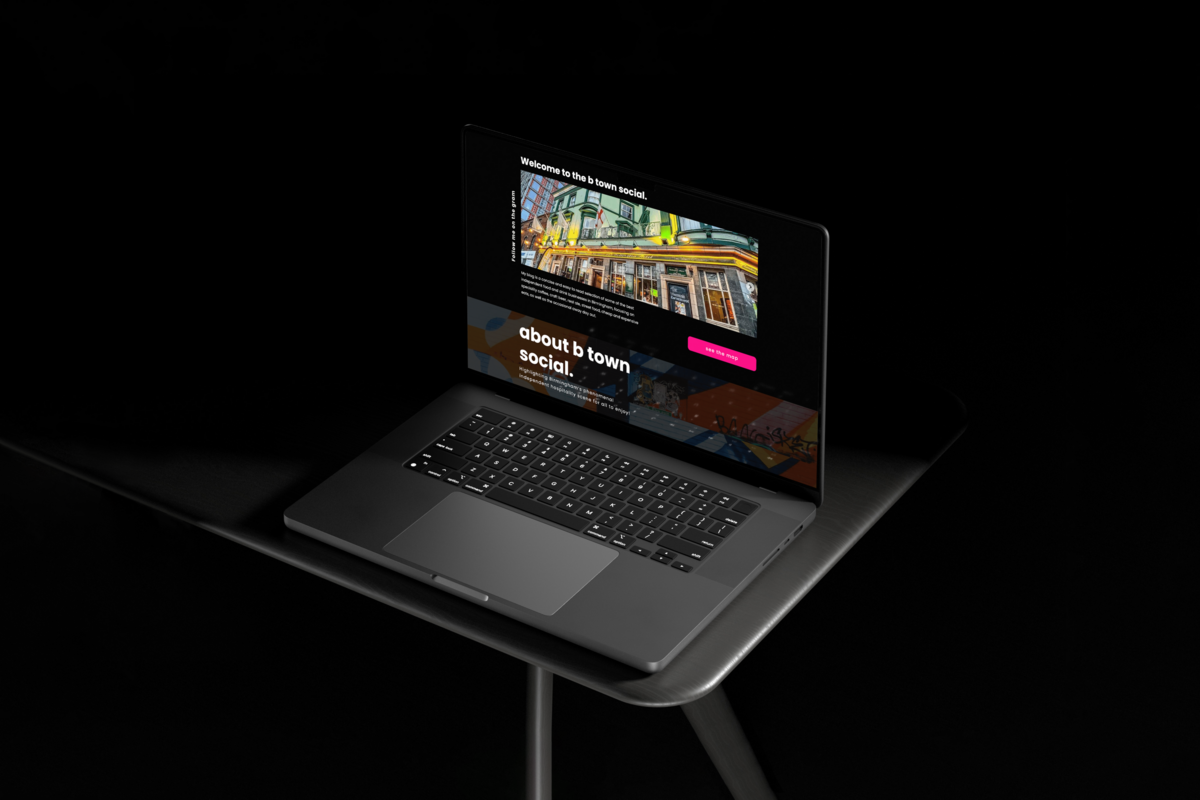 A laptop displaying the homepage of the B Town Social website, placed on a dark surface against a black background. The screen features a vibrant image of a colourful building facade and text sections introducing B Town Social, which highlights Birmingham's independent hospitality scene. A prominent pink button invites users to "View the blog" The overall aesthetic is modern and visually appealing, focusing on community and social engagement.