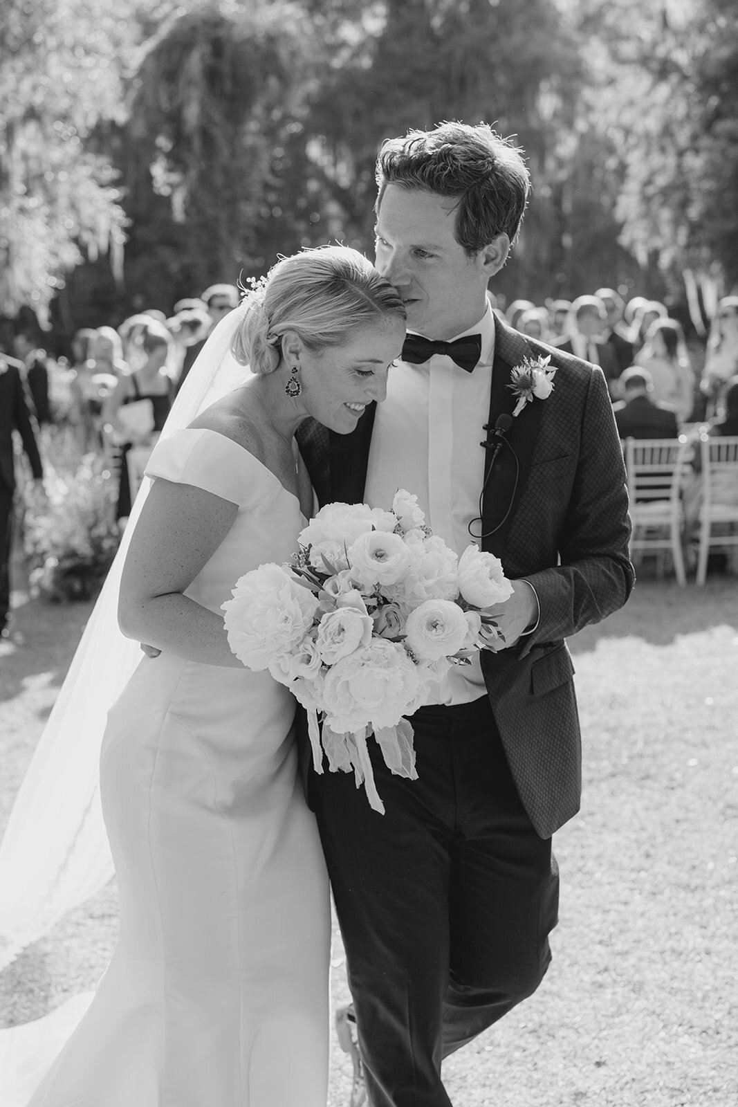 Bride and groom intimate black and white moment after exiting the outdoor wedding ceremony at Magnolia Gardens.