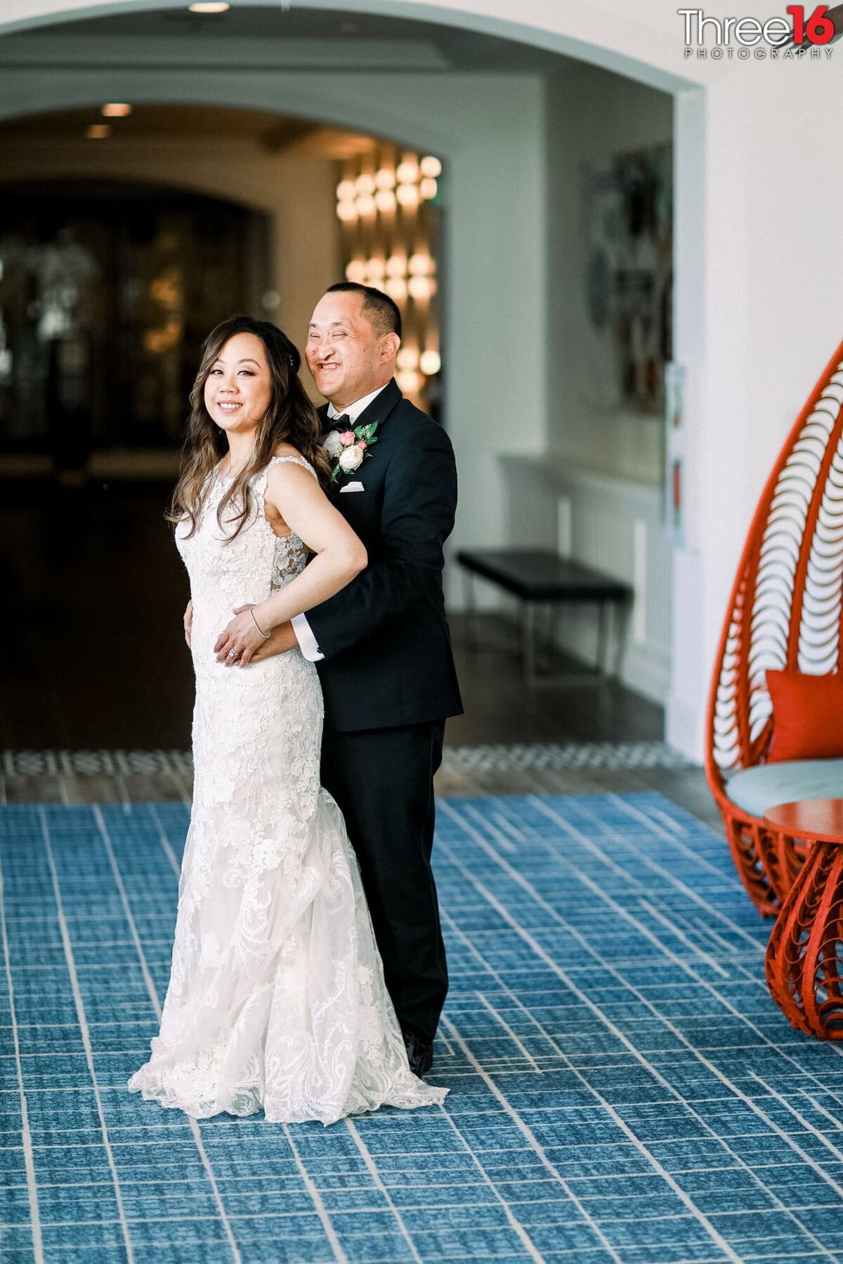 Groom holds onto his Bride from behind as they pose for after wedding photos