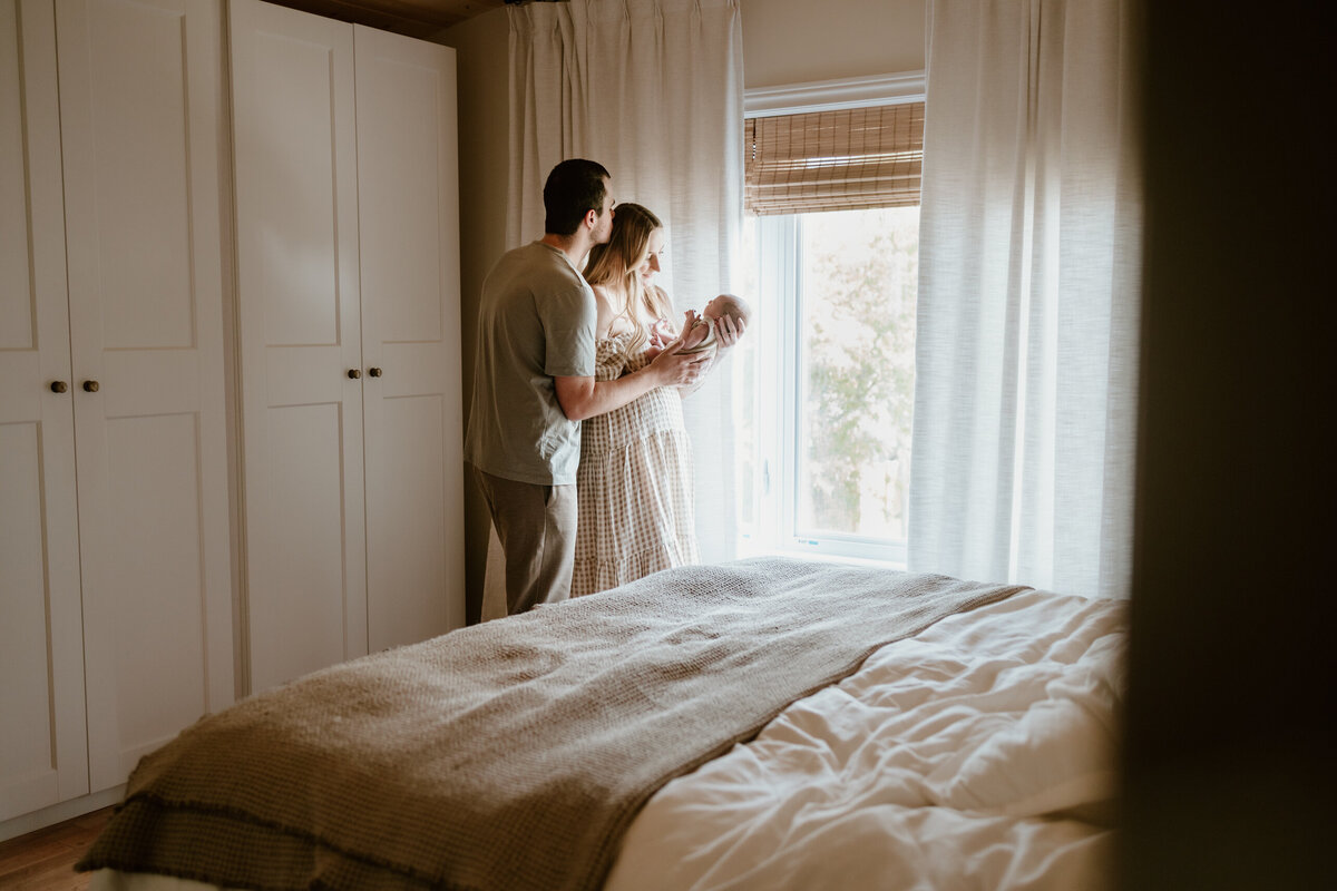 Parents holding newborn by window