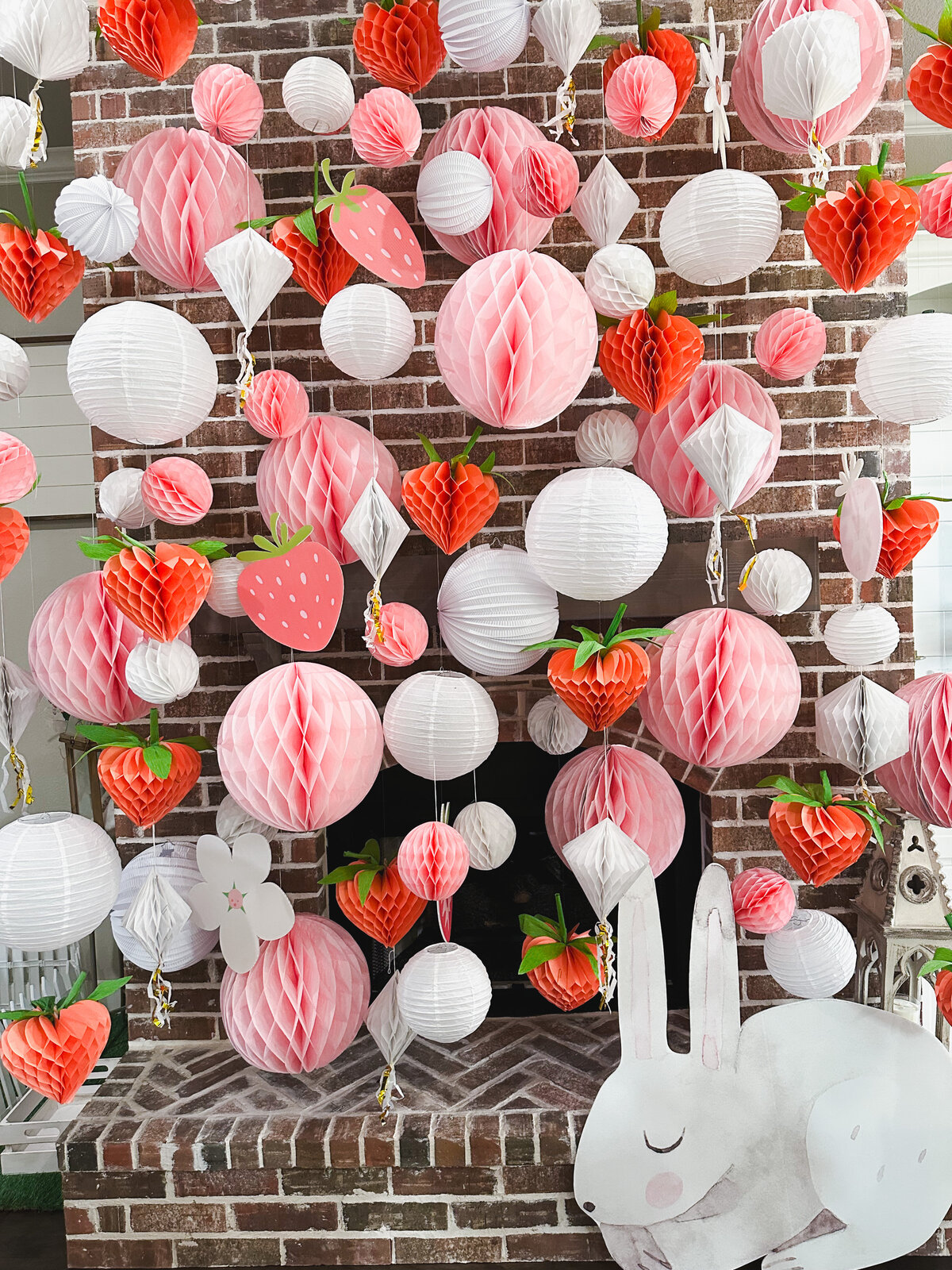 Pink and white honecomb wall with pink and white tissues and large bunny cutout.