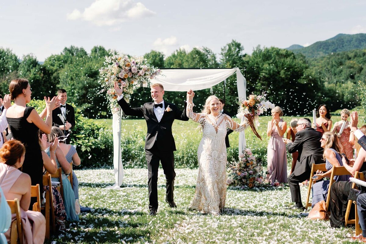 just married couple walking down the aisle with confetti in the air and jubilance all around by jaclyn watson events
