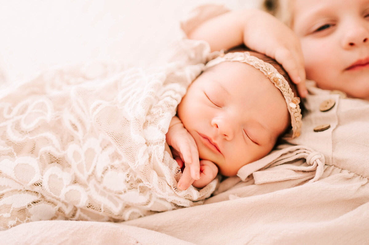sleeping newborn baby girl on sisters chest captured in Springfield MO newborn photography studio