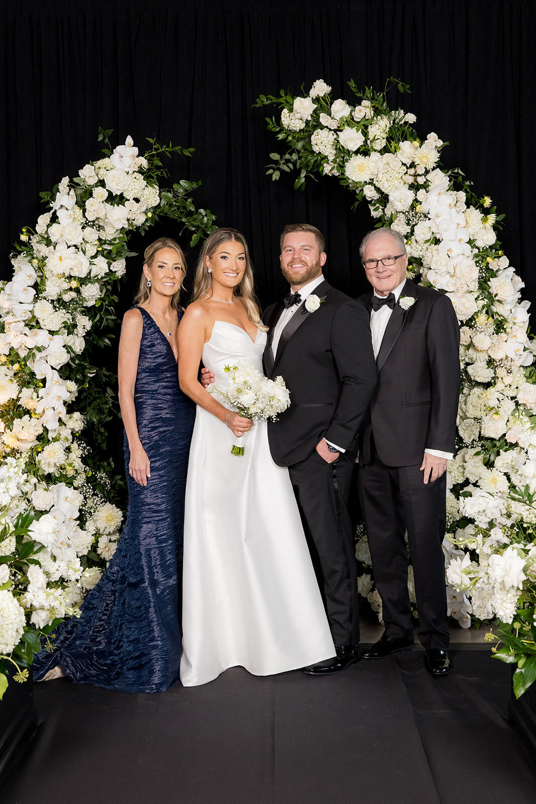 newlyweds-with-brides-parents-while-arched-flowers-revel-motor-row-HBICWeddings