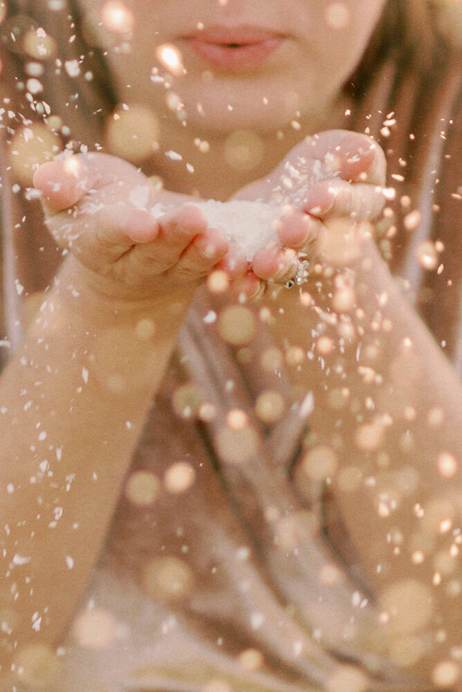 Woman blowing glitter at her Christmas maternity photoshoot