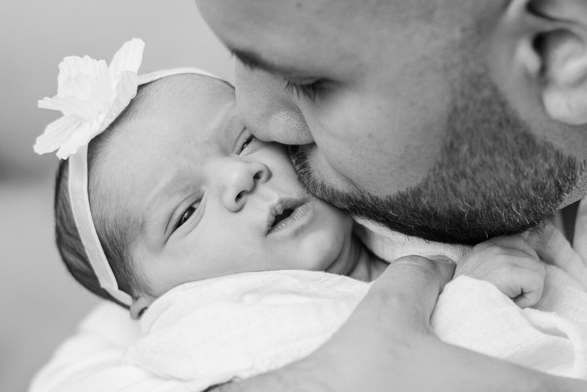 dad-kisses-his-newborn-baby-girl-in-black-and-white