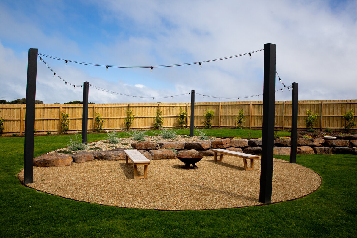 An outdoor space for entertaining with seating and fireplace surrounded by a rock wall
