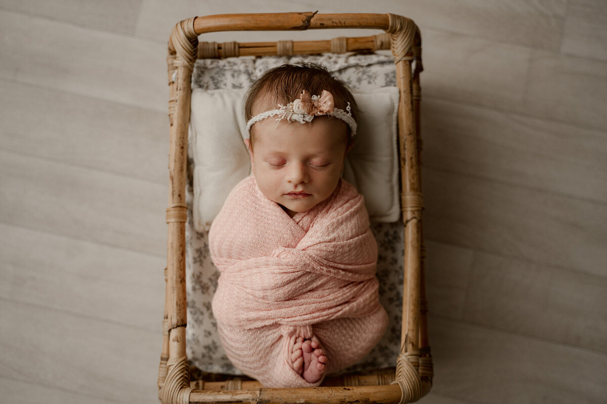 Dothan AL Newborn Photos; baby girl in a pink wrap in a crib