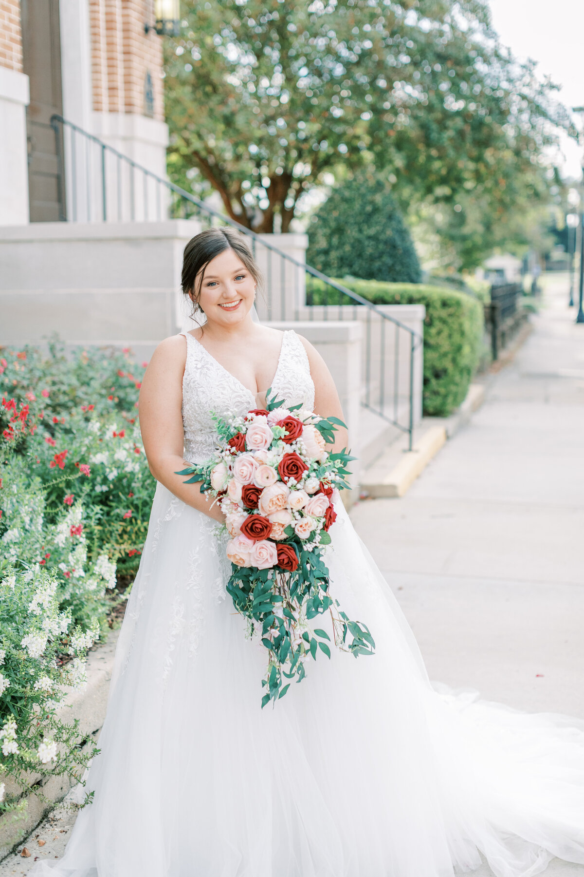 A bride holds her bouquet while standing in front of a church.