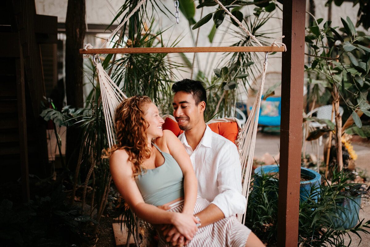 Hawaii couples session in Oahu. Cute couple looking at each other in hammock chair.