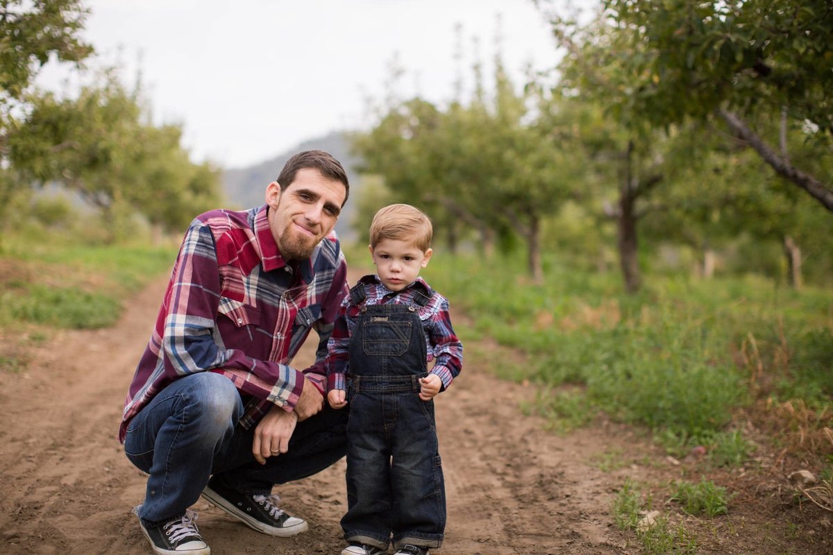Young boy poses with his kneeling dad during a hike at Riley's Farm