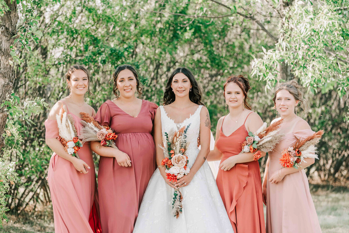 The bride and her bridesmaids standing together outside. 