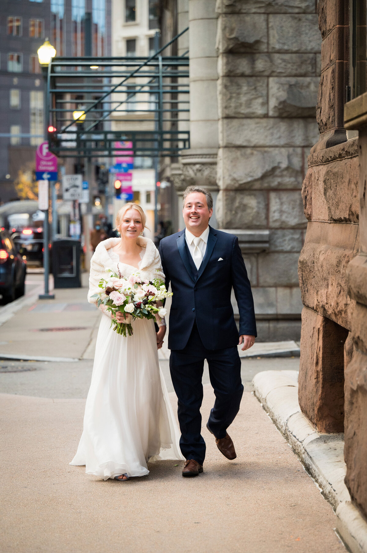 pittsburgh couple walking down the street taking wedding photos near the duquesne club