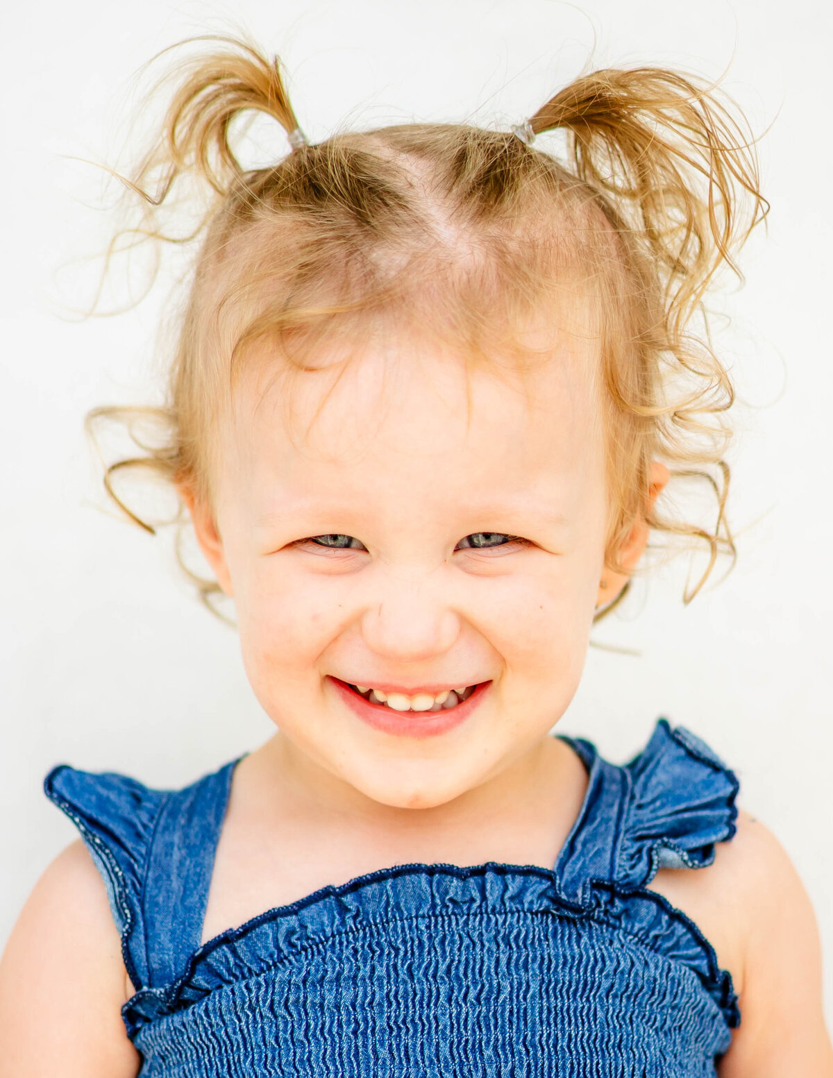 Close-up of toddler girl with gentle expression and soft lighting on white background